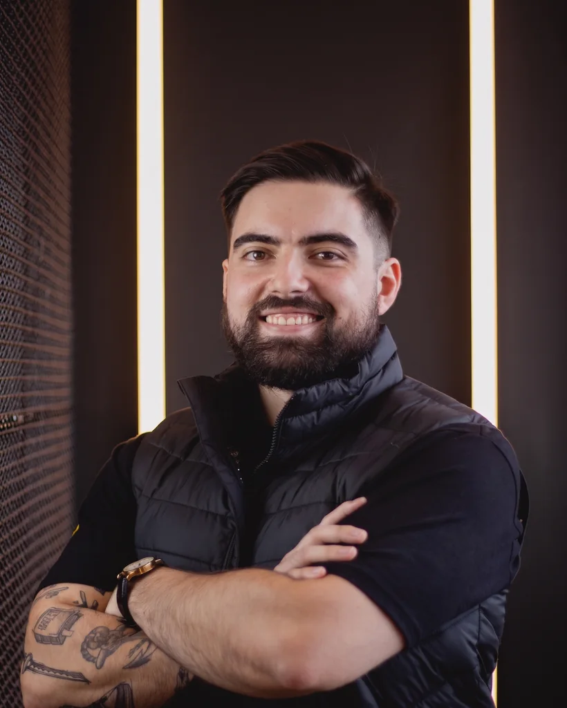 Felipe Santos sorrindo, de braços cruzados